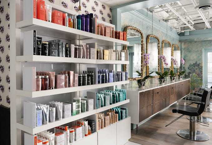 Elegant salon interior with shelves of hair products and stylish mirror stations.